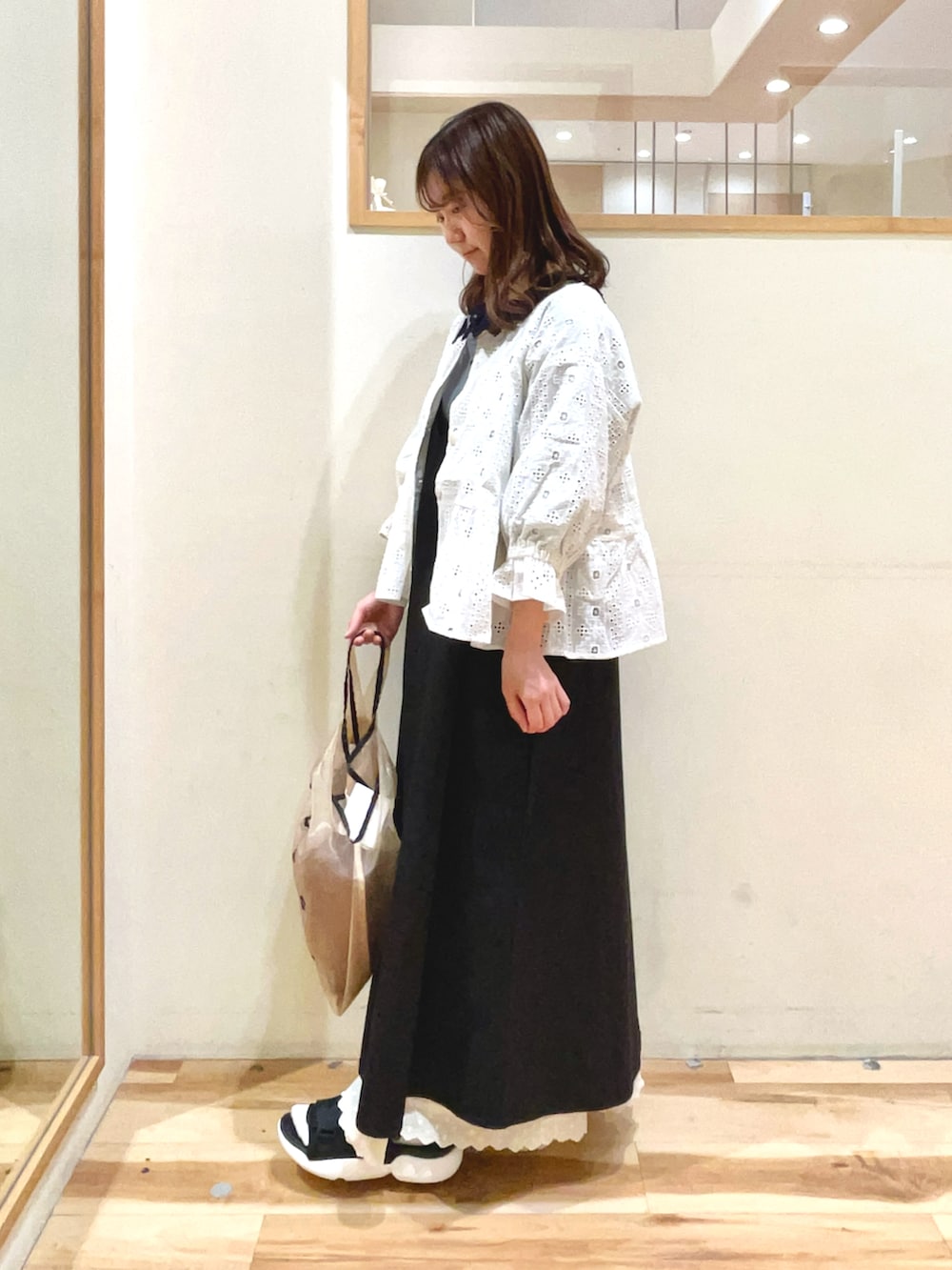 ベージュ系のハンドバッグ、ブラック系のサンダル、ブラック系のワンピースを着用したレディースの春コーディネートの2枚目の写真