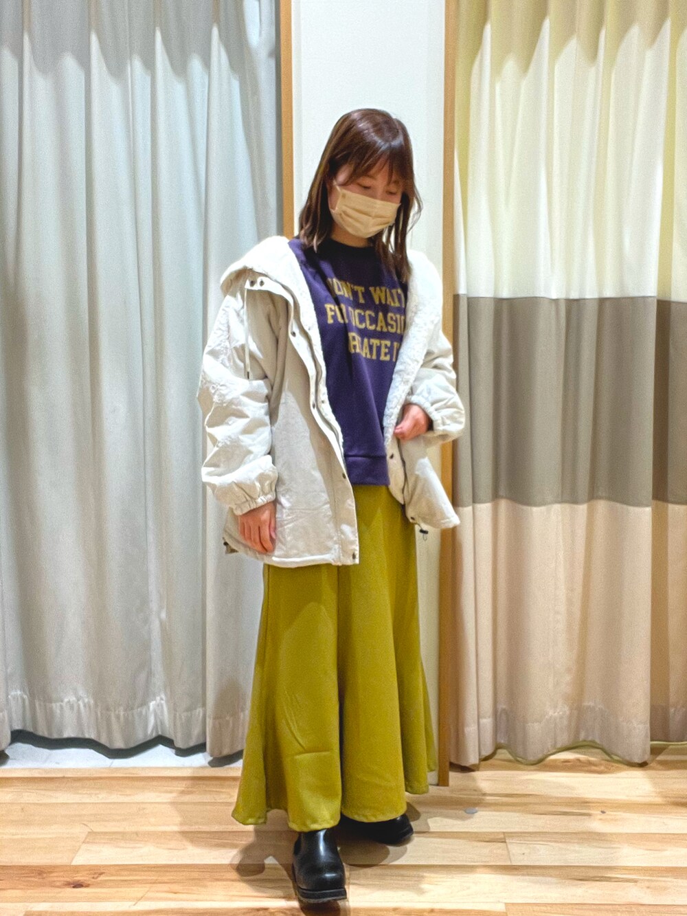 パープル系のTシャツ/カットソー、ホワイト系のマウンテンパーカー、イエロー系のスカートを着用したレディースの冬コーディネートの2枚目の写真