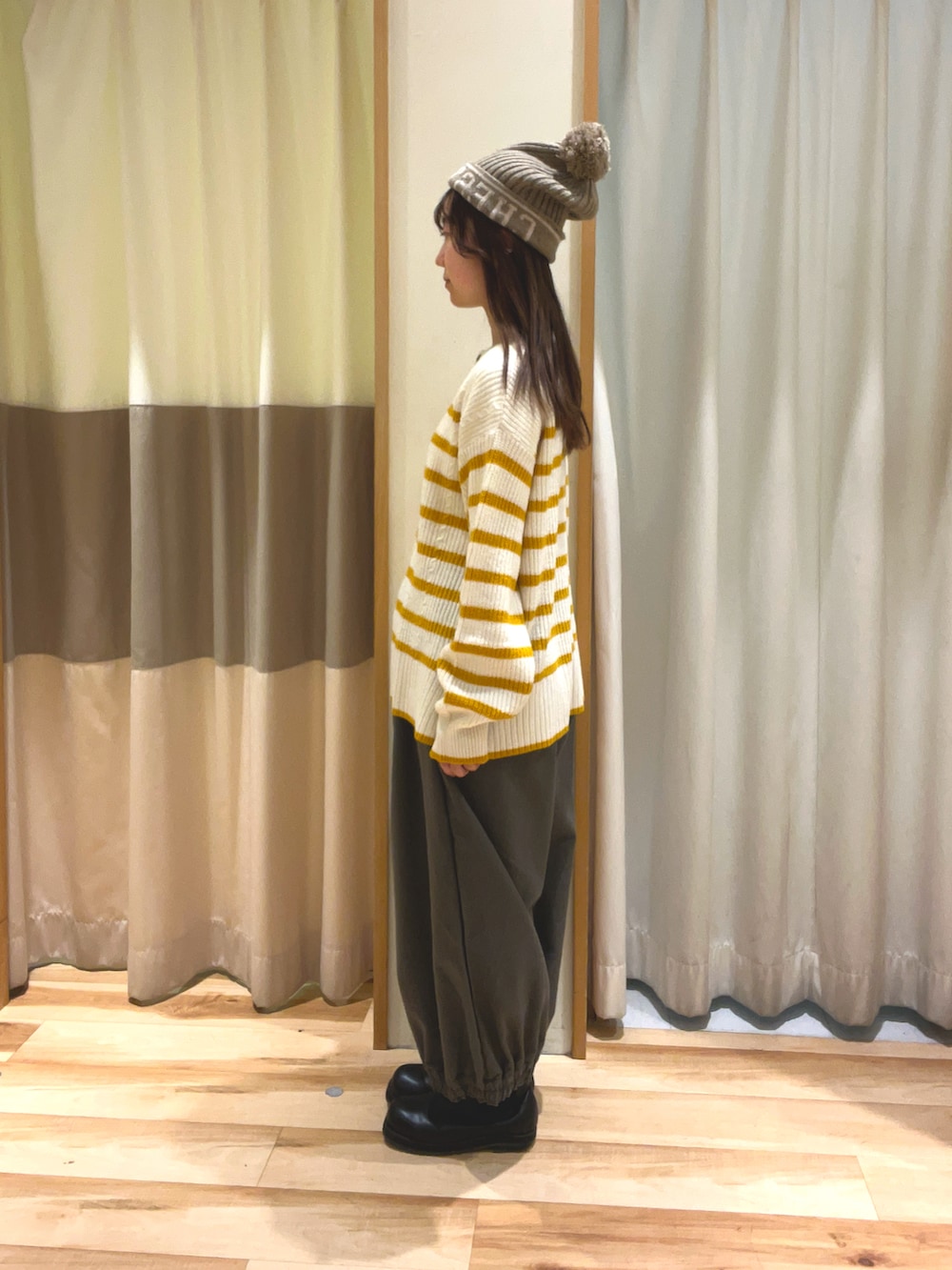 ブラウン系のその他パンツ、イエロー系のカーディガン/ボレロ、ブラウン系のニットキャップ/ビーニーを着用したレディースの冬コーディネートの3枚目の写真