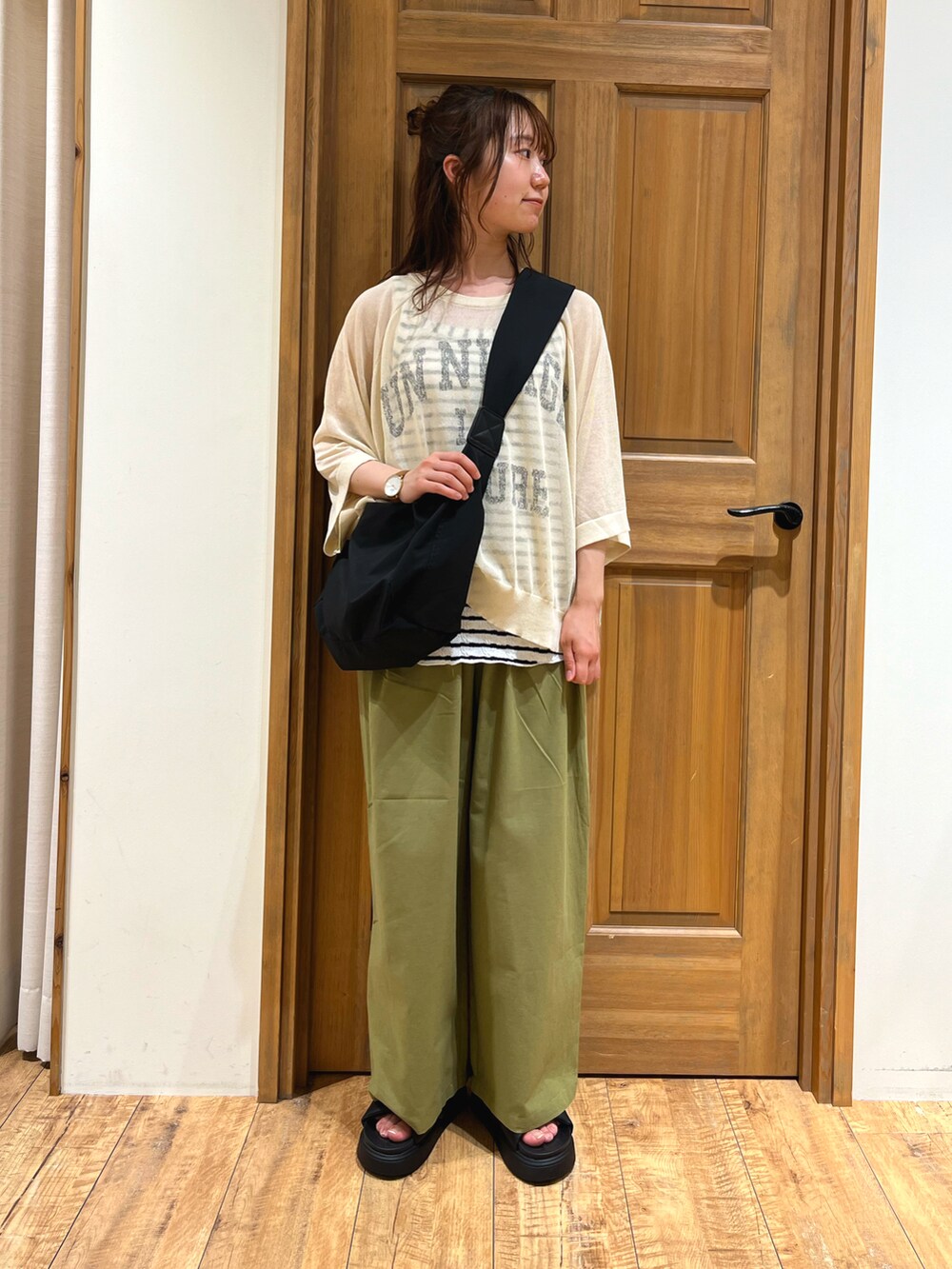 ブラック系のハンドバッグ、ベージュ系のニット/セーター、ホワイト系のTシャツ/カットソーを着用したレディースの夏コーディネートの2枚目の写真