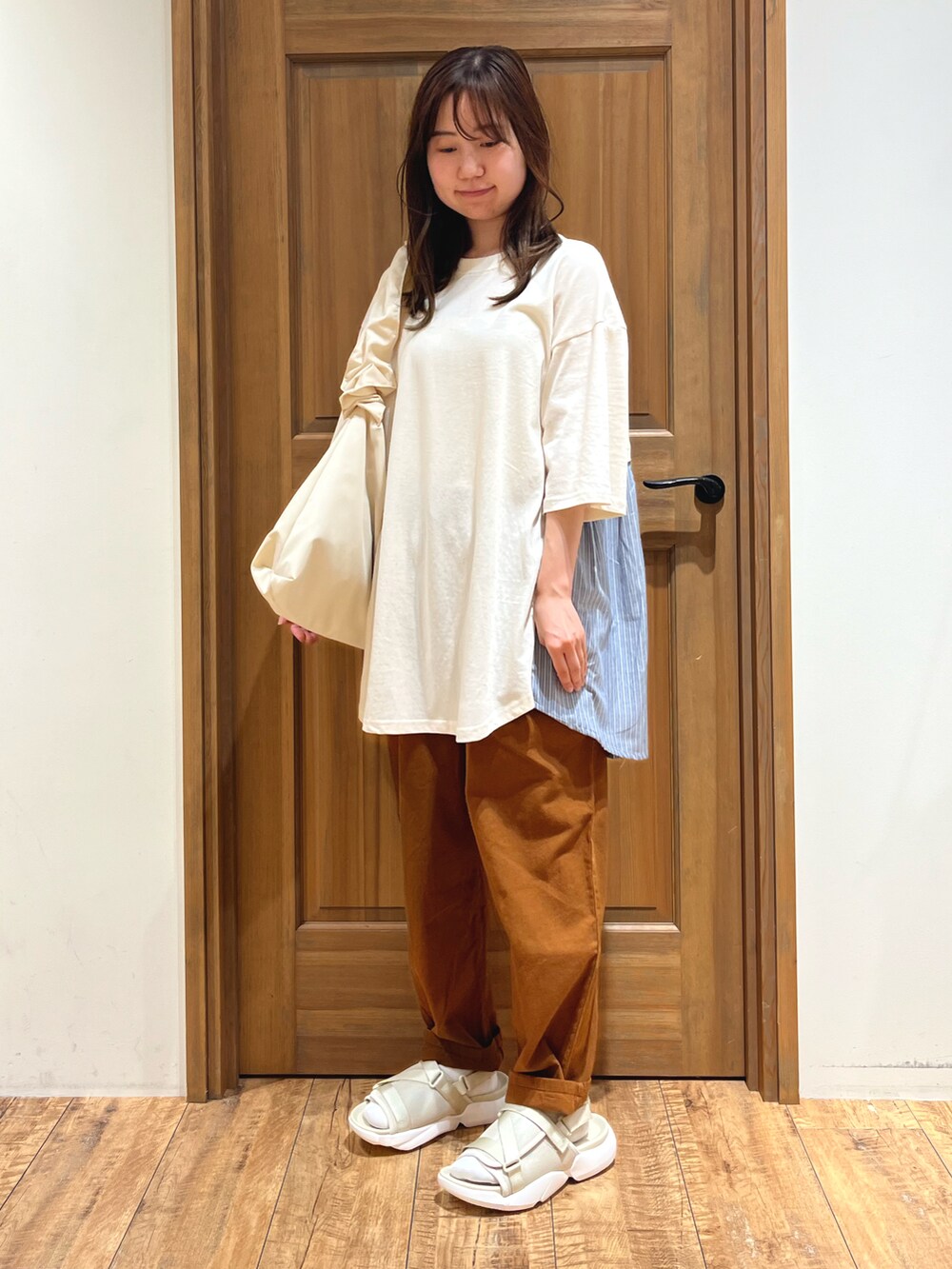 ホワイト系のハンドバッグ、ブラウン系のその他パンツ、ベージュ系のサンダルを着用したレディースの夏コーディネートの2枚目の写真