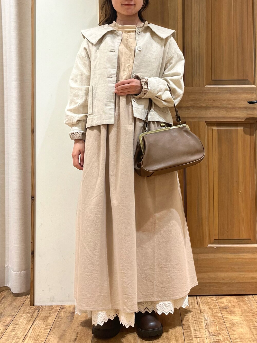 ブラウン系のブーツ、ブラウン系のハンドバッグ、ホワイト系のノーカラージャケットを着用したレディースの秋コーディネートの2枚目の写真