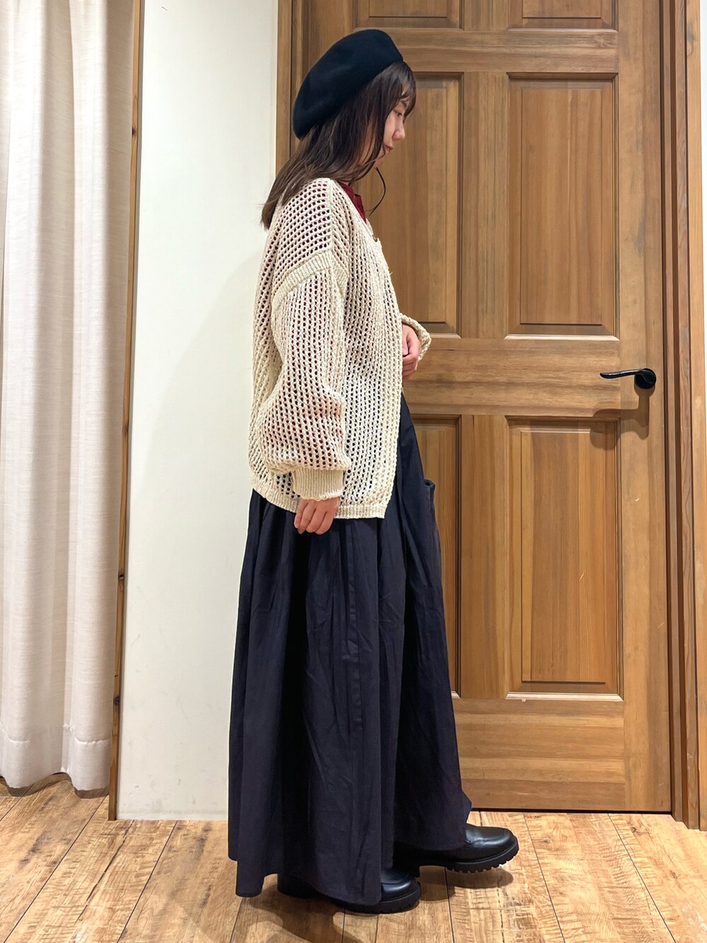 グレー系のハンドバッグ、グレー系のスカート、レッド系のニット/セーターを着用したレディースの秋コーディネートの4枚目の写真