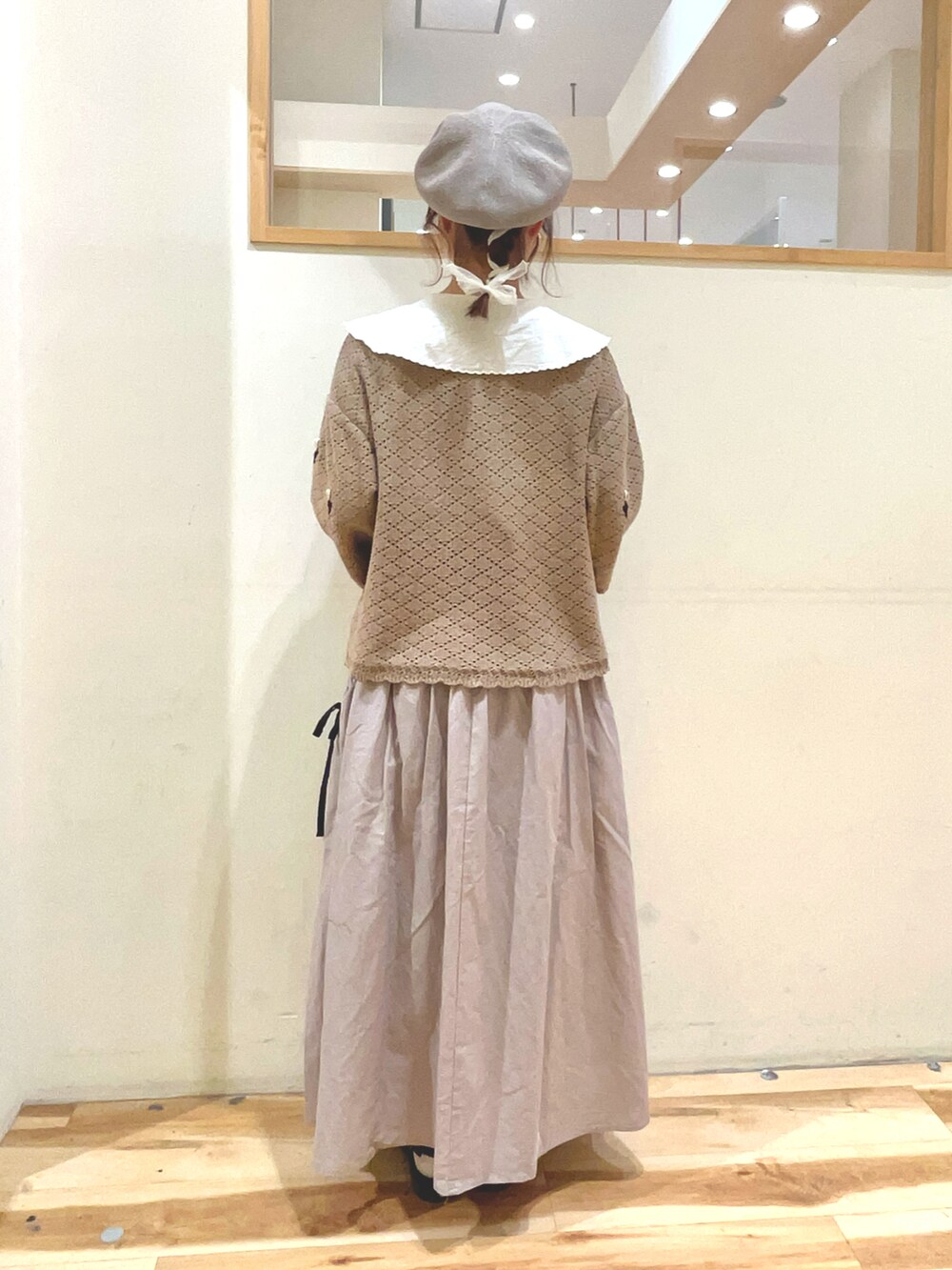 シルバー系のハンドバッグ、ベージュ系のスカート、ブラック系のサンダルを着用したレディースの春コーディネートの5枚目の写真