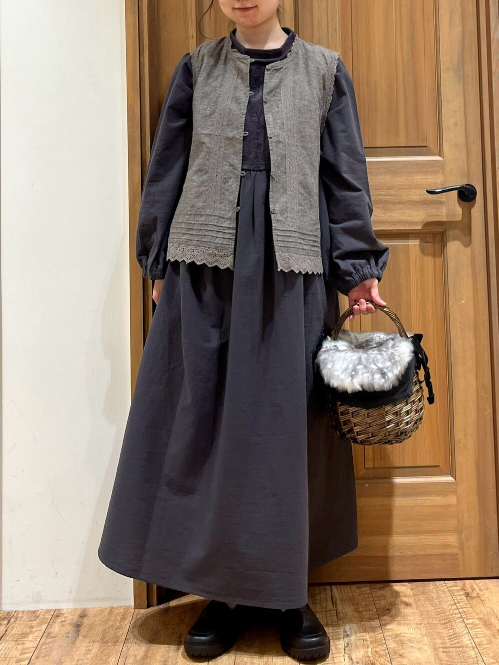 ブラウン系のバッグ、ブラック系のドレスシューズ、グレー系のベストを着用したレディースの秋コーディネートの4枚目の写真