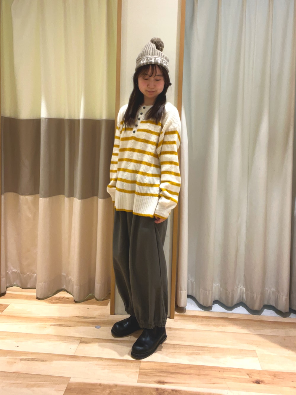 ブラウン系のその他パンツ、イエロー系のカーディガン/ボレロ、ブラウン系のニットキャップ/ビーニーを着用したレディースの冬コーディネートの2枚目の写真