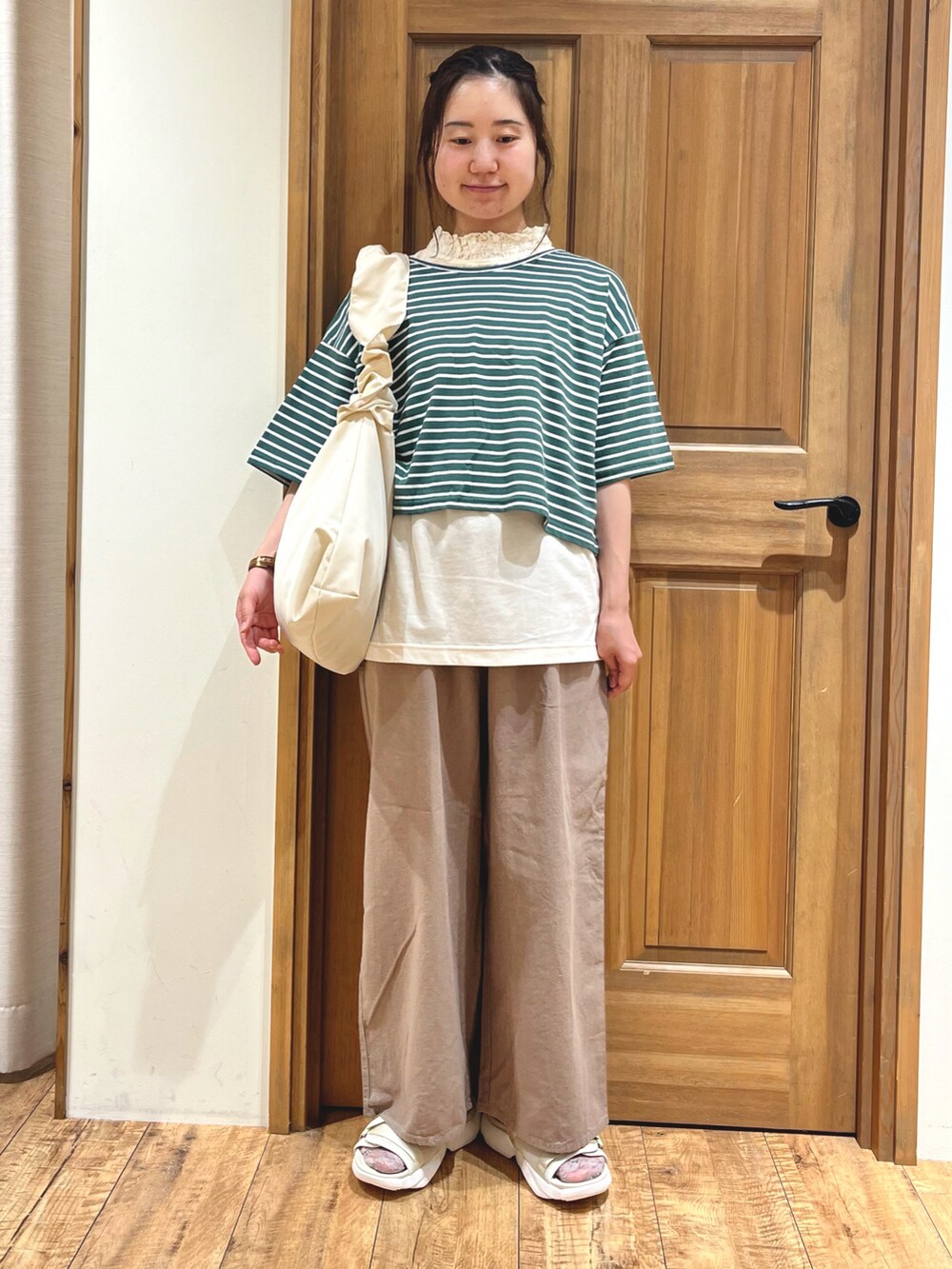 ベージュ系のサンダル、ホワイト系のハンドバッグ、ブラウン系のその他パンツを着用したレディースの夏コーディネートの2枚目の写真