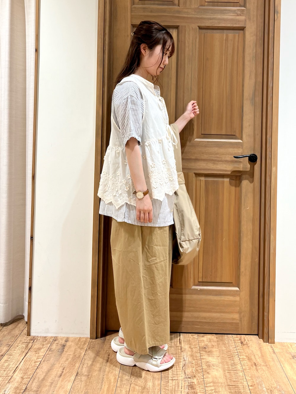 ベージュ系のハンドバッグ、ホワイト系のベスト、ブルー系のシャツ/ブラウスを着用したレディースの夏コーディネートの3枚目の写真