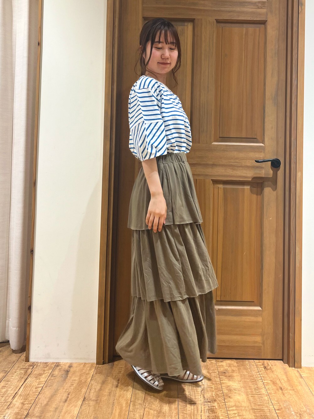 シルバー系のサンダル、ブルー系のTシャツ/カットソー、グリーン系のスカートを着用したレディースの夏コーディネートの2枚目の写真