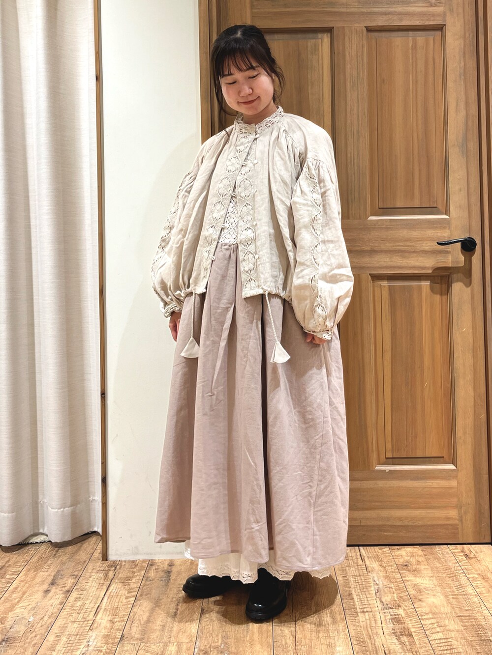 ブラック系のブーツ、ホワイト系のスカート、ベージュ系のノーカラージャケットを着用したレディースの秋コーディネートの2枚目の写真