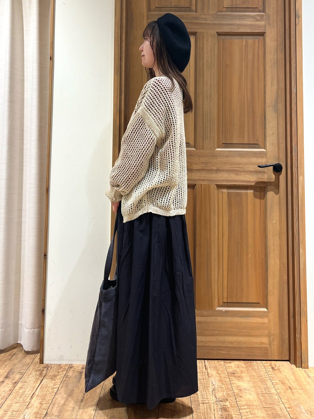 グレー系のハンドバッグ、グレー系のスカート、レッド系のニット/セーターを着用したレディースの秋コーディネートの3枚目の写真