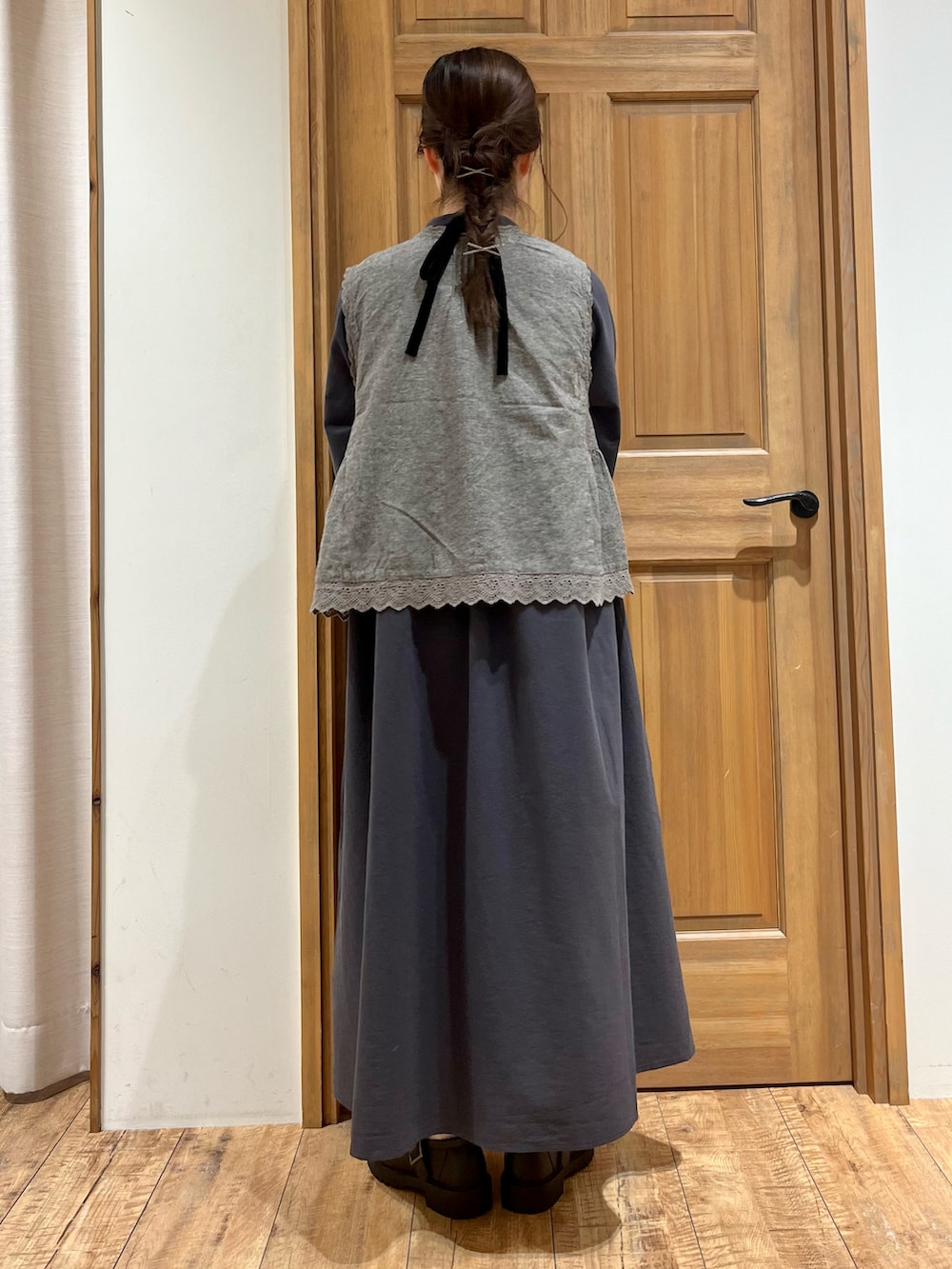 ブラウン系のバッグ、ブラック系のドレスシューズ、グレー系のベストを着用したレディースの秋コーディネートの2枚目の写真