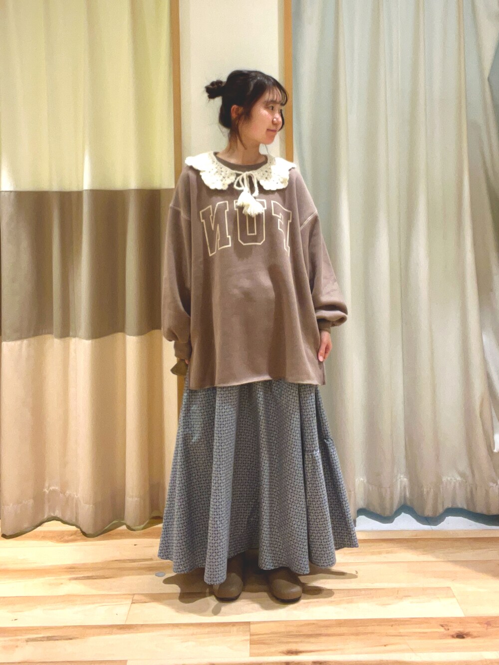 グリーン系のスカート、ブラウン系のTシャツ/カットソー、ベージュ系のブーツを着用したレディースの冬コーディネートの2枚目の写真