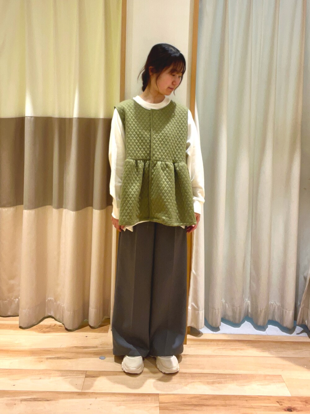 ホワイト系のTシャツ/カットソー、グリーン系のベスト、ブラック系のハンドバッグを着用したレディースの冬コーディネートの3枚目の写真