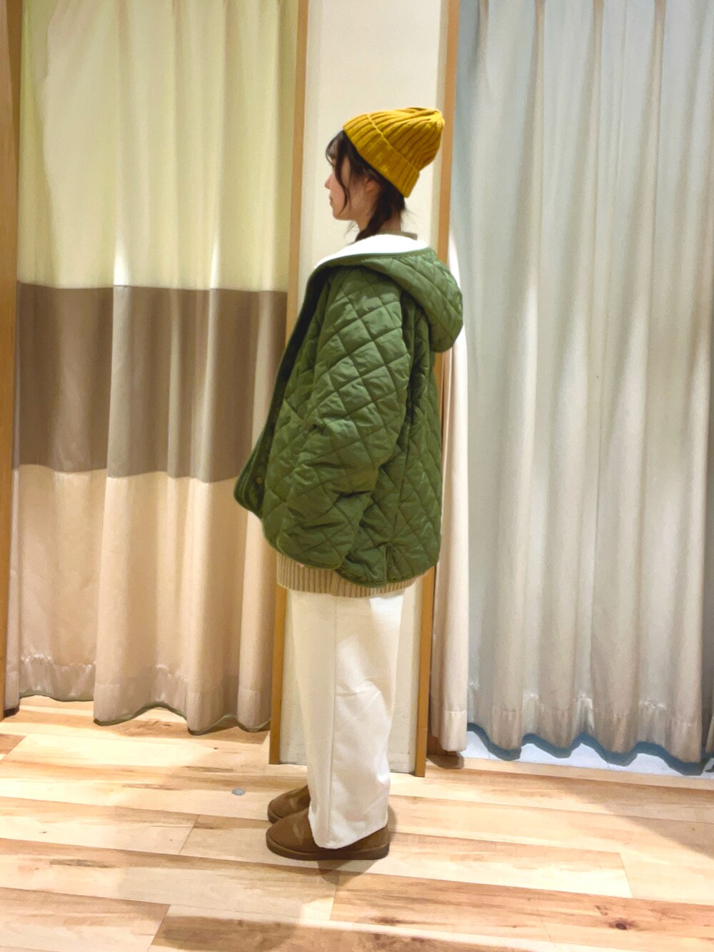 グリーン系のブルゾン、ベージュ系のニット/セーター、ホワイト系のその他パンツを着用したレディースの冬コーディネートの2枚目の写真