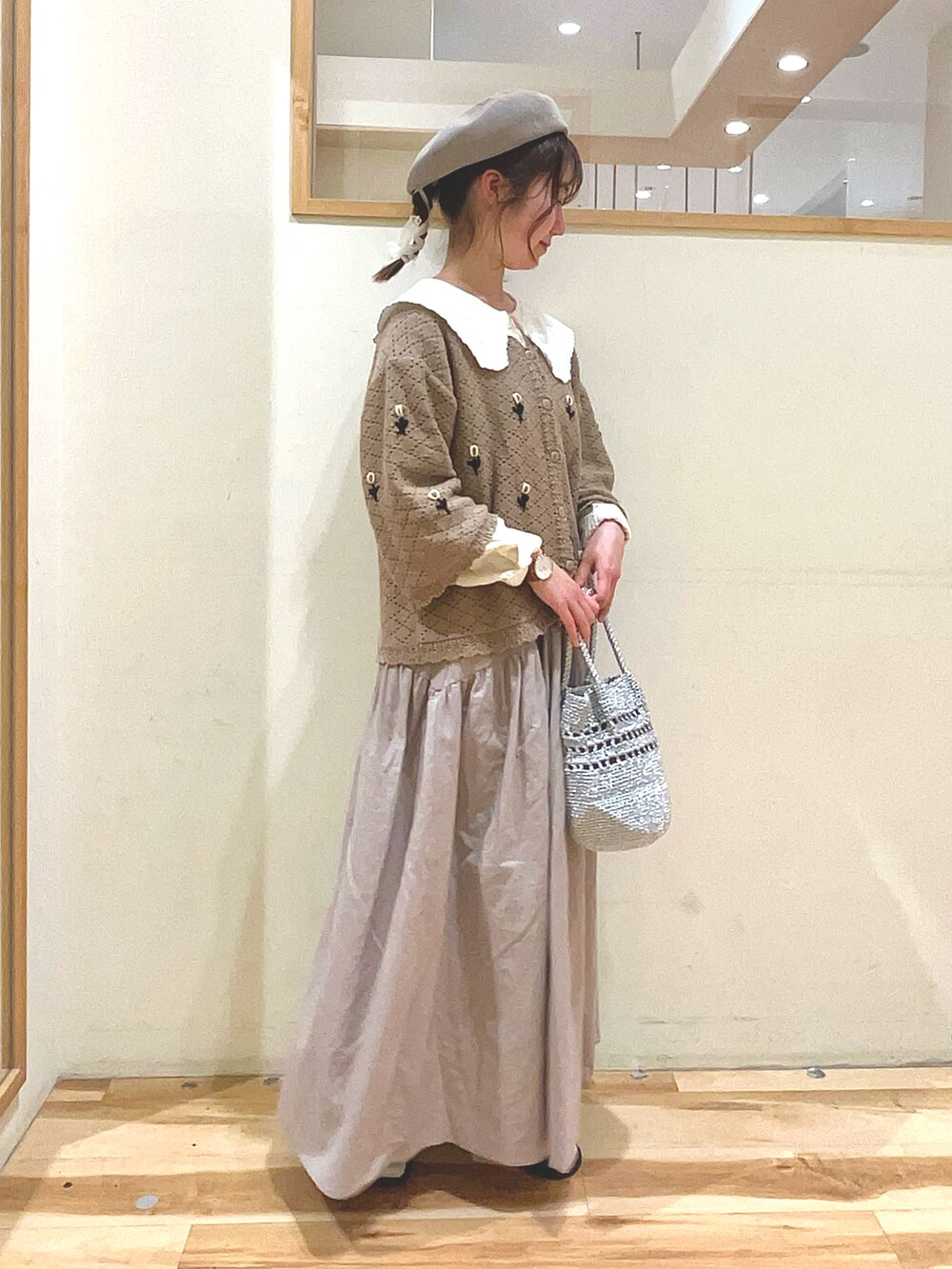 シルバー系のハンドバッグ、ベージュ系のスカート、ブラック系のサンダルを着用したレディースの春コーディネートの3枚目の写真