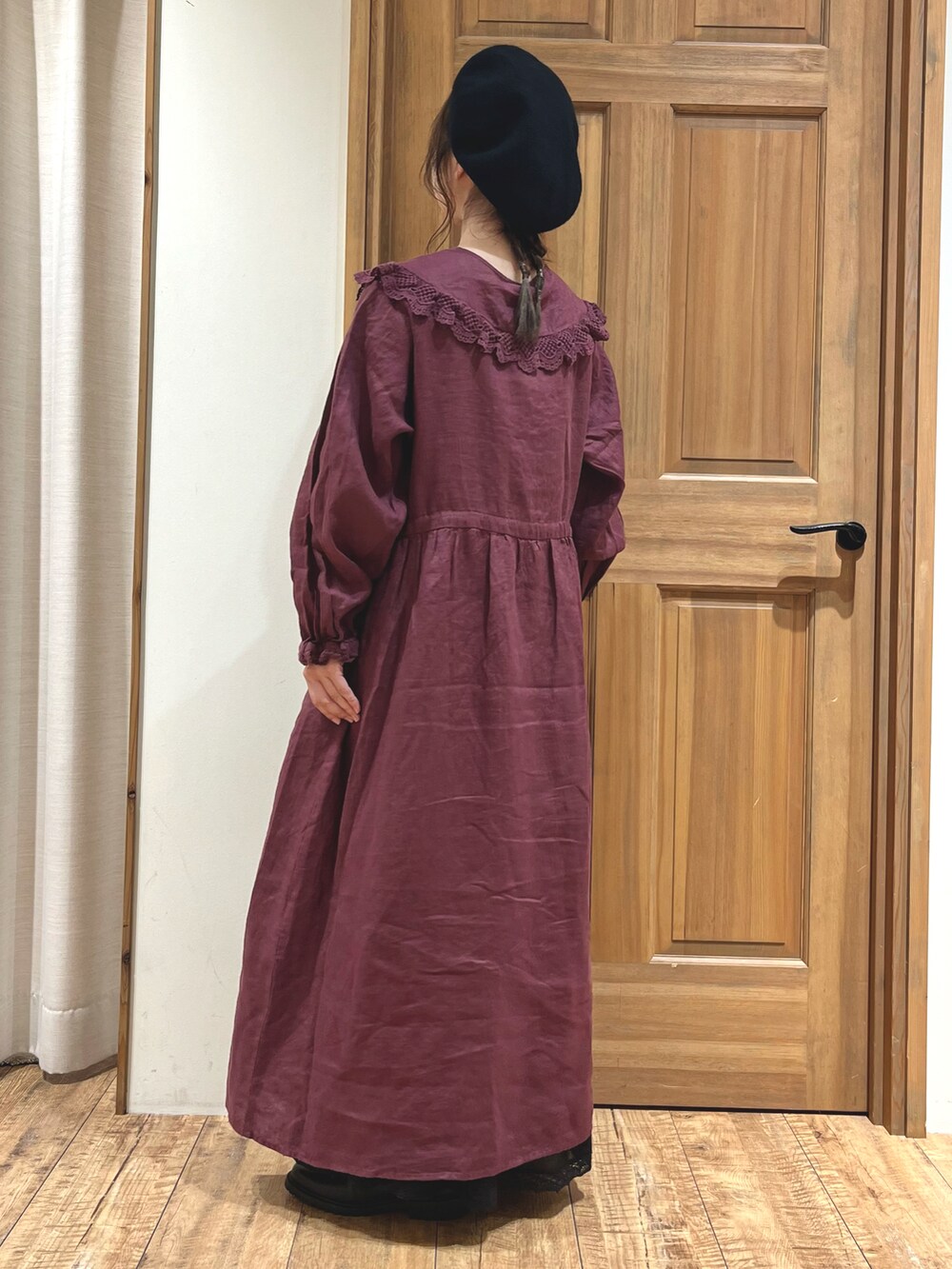 レッド系のワンピース、ブラック系のスカート、ブラック系のブーツを着用したレディースの秋コーディネートの3枚目の写真