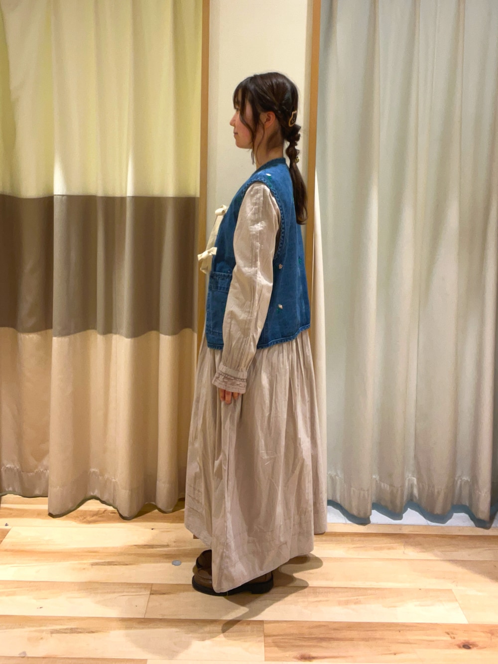 ベージュ系のワンピース、ブルー系のベストを着用したレディースの冬コーディネートの3枚目の写真