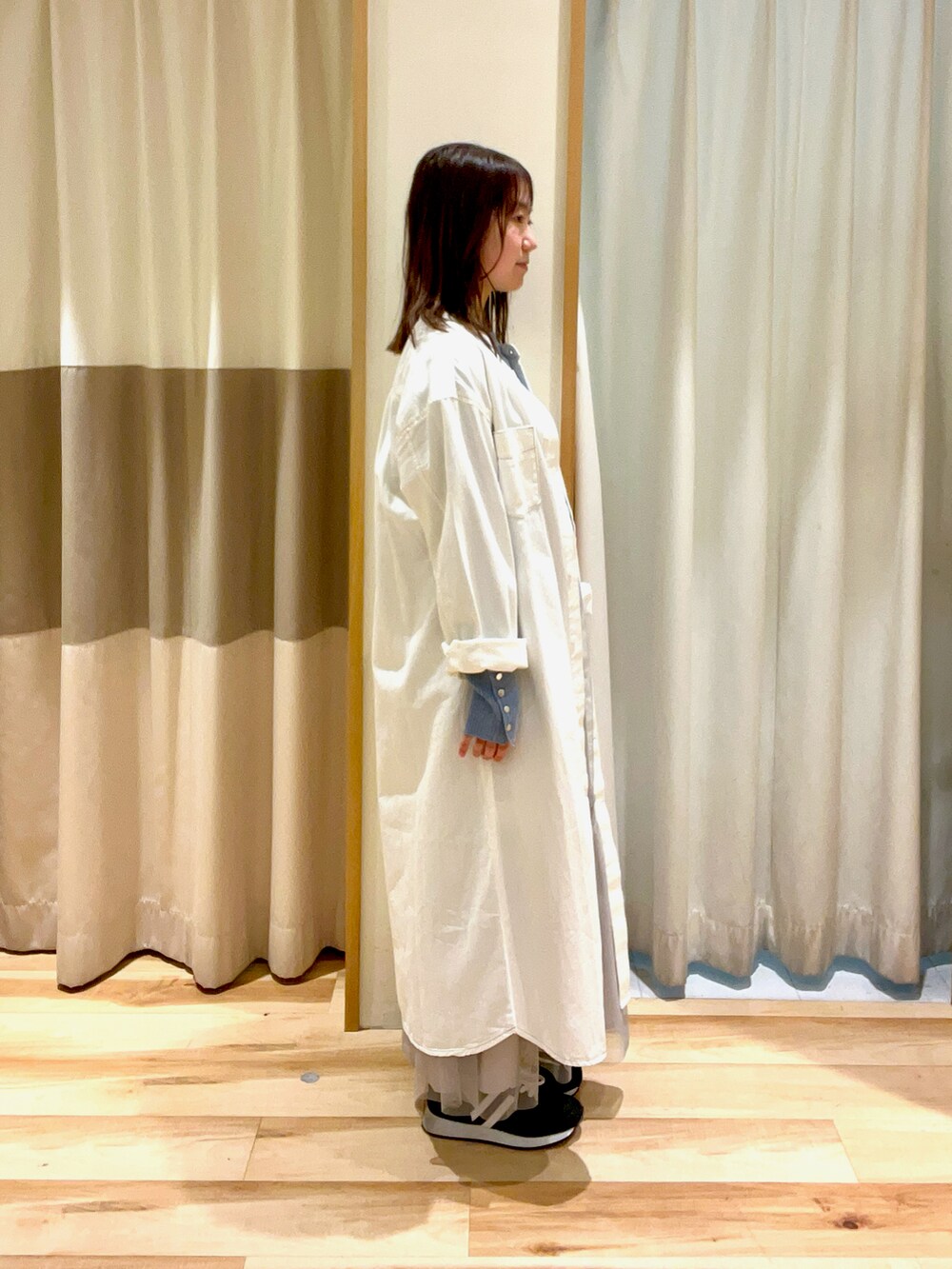 ブルー系のニット/セーター、グレー系のスカート、ホワイト系のワンピースを着用したレディースの春コーディネートの3枚目の写真