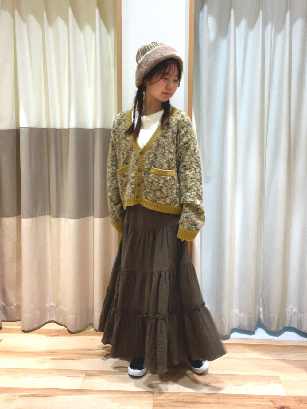 イエロー系のカーディガン/ボレロ、グリーン系のスカート、ホワイト系のTシャツ/カットソーを着用したレディースの冬コーディネートの2枚目の写真