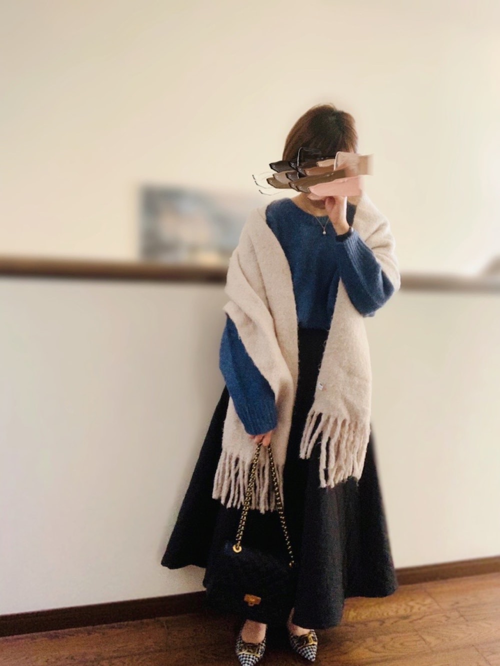 ブルー系のニット/セーター、ブラック系のクラッチバッグ、ブラック系のスカートを着用したレディースの秋コーディネートの2枚目の写真