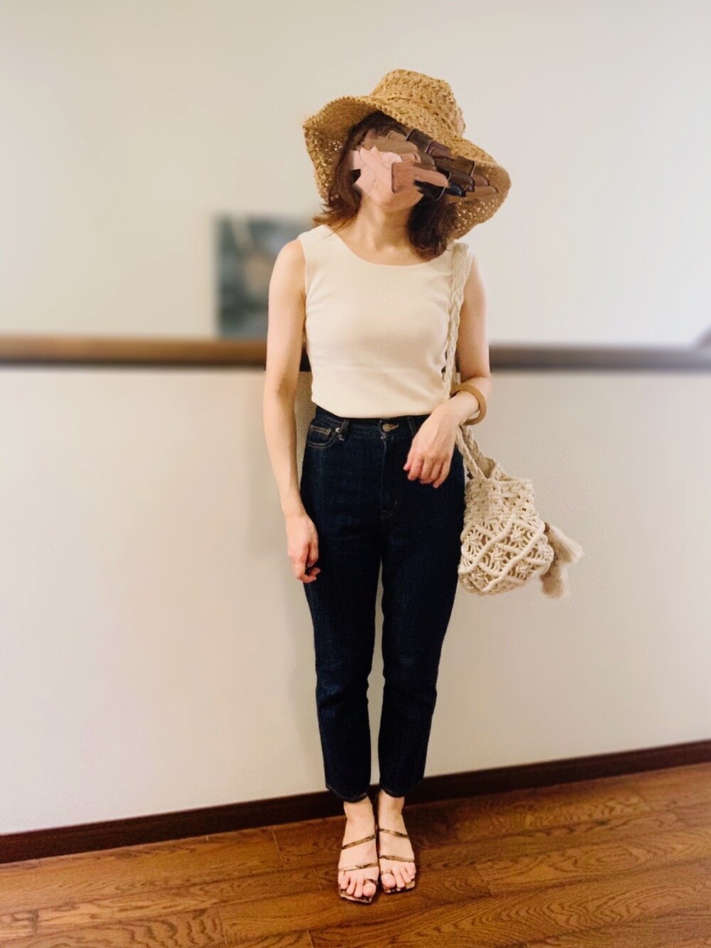 ベージュ系のタンクトップ、ホワイト系のショルダーバッグ、ブルー系のデニムパンツを着用したレディースの夏コーディネートの2枚目の写真