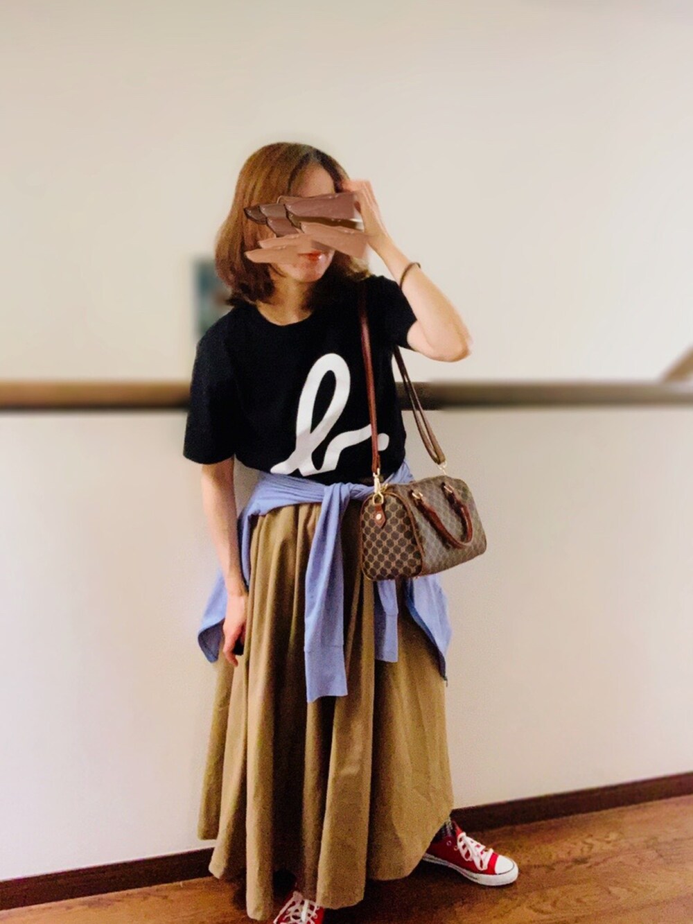 ブラック系のTシャツ/カットソー、ベージュ系のスカート、レッド系のスニーカーを着用したレディースの夏コーディネートの2枚目の写真