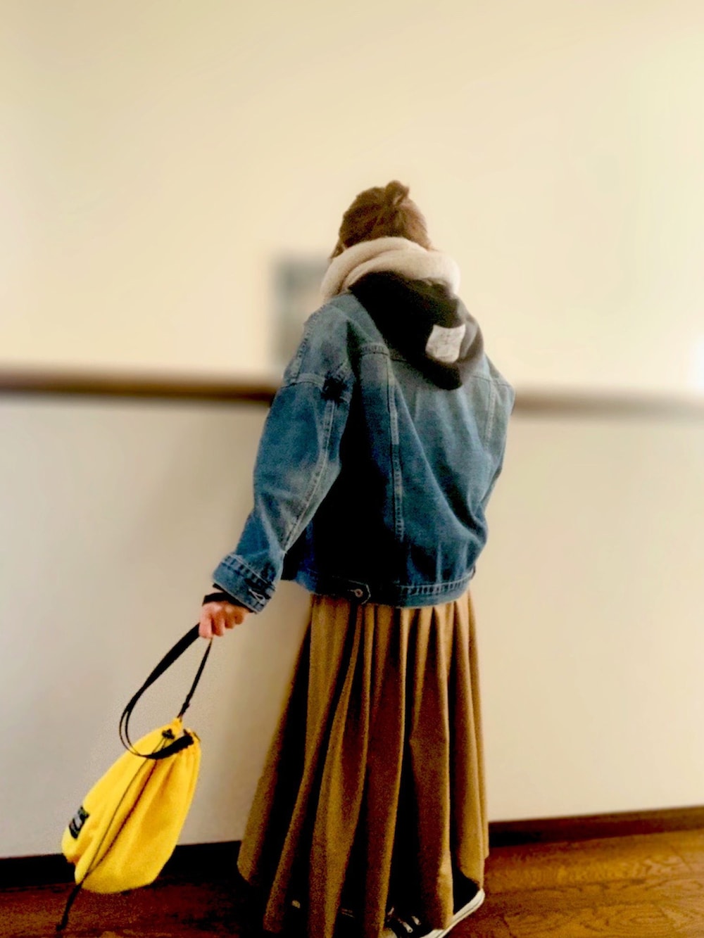 ブルー系のデニムジャケット、ベージュ系のスカート、ブラック系のスニーカーを着用したレディースの冬コーディネートの2枚目の写真