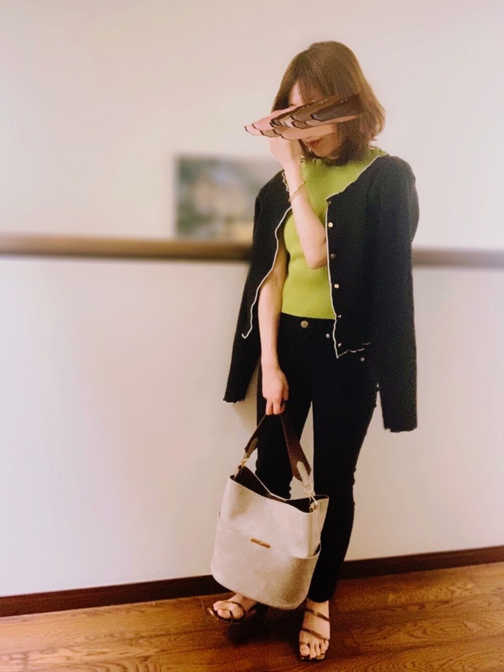 グリーン系のニット/セーター、ブラック系のカーディガン/ボレロ、ブラック系のデニムパンツを着用したレディースの春コーディネートの2枚目の写真