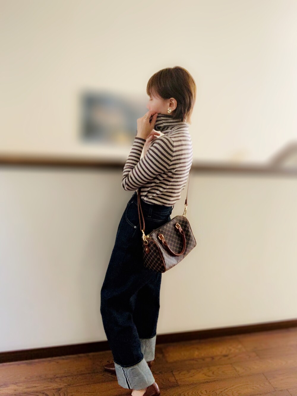 ベージュ系のニット/セーター、ブラウン系のボストンバッグ、ブルー系のデニムパンツを着用したレディースの秋コーディネートの2枚目の写真