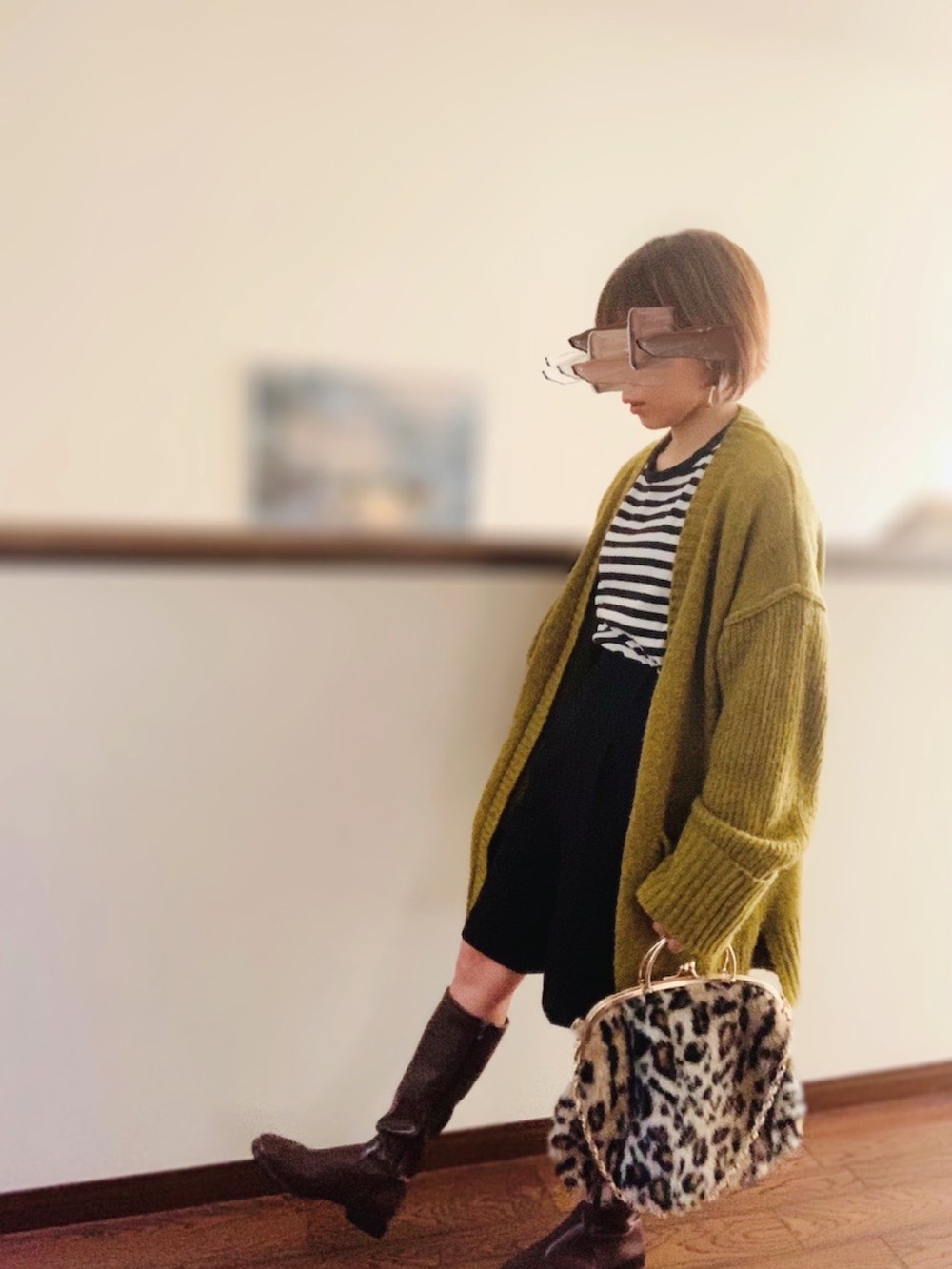 ブラック系のTシャツ/カットソー、グリーン系のカーディガン/ボレロ、ブラウン系のブーツを着用したレディースの秋コーディネートの2枚目の写真