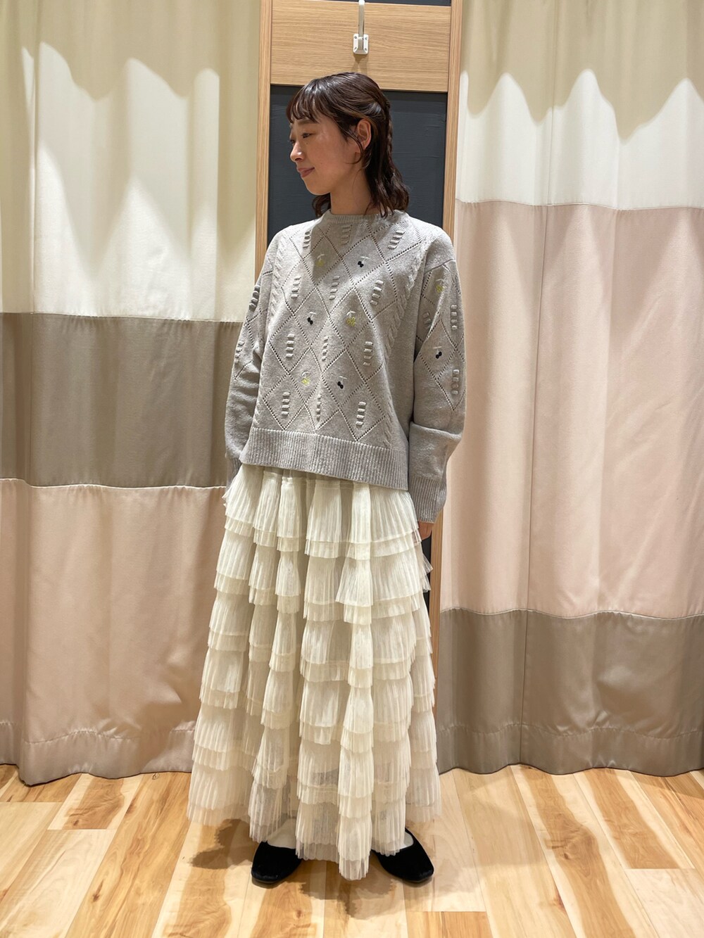 ブラウン系のニット/セーター、ホワイト系のスカートを着用したレディースの秋コーディネートの3枚目の写真