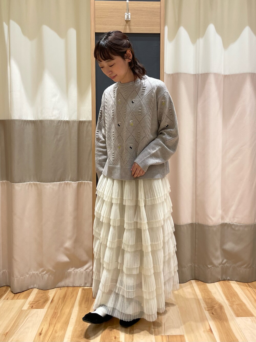 ブラウン系のニット/セーター、ホワイト系のスカートを着用したレディースの秋コーディネートの2枚目の写真