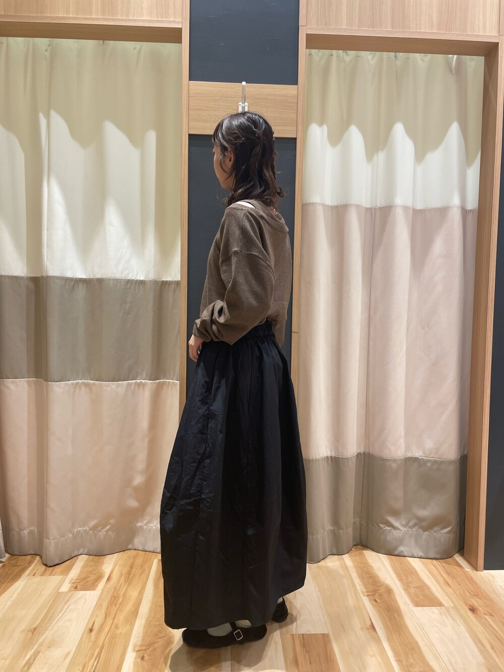 ブラウン系のニット/セーター、ブラック系のスカートを着用したレディースの秋コーディネートの2枚目の写真