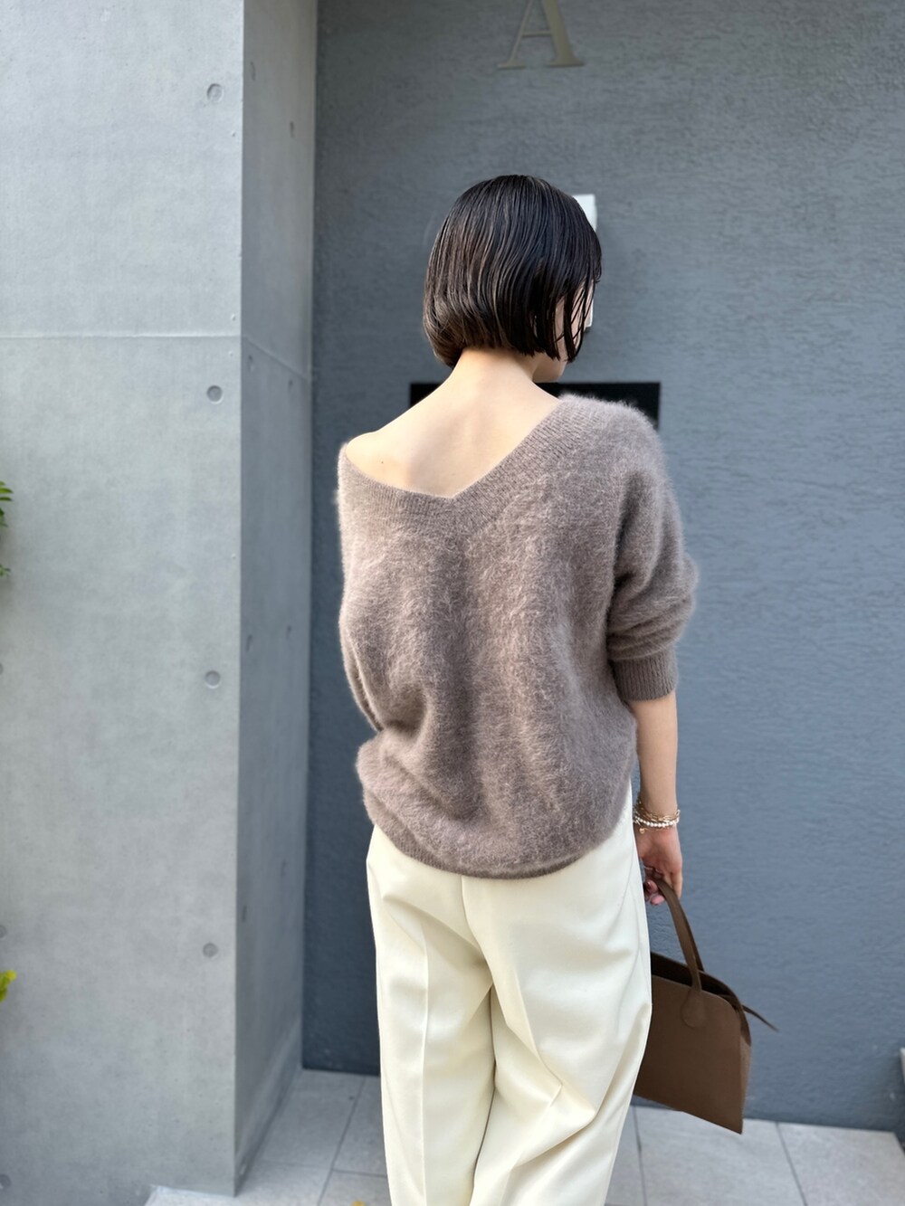 ブラウン系のニット/セーター、ブラウン系のボストンバッグ、ホワイト系のその他パンツを着用したレディースの秋コーディネートの4枚目の写真