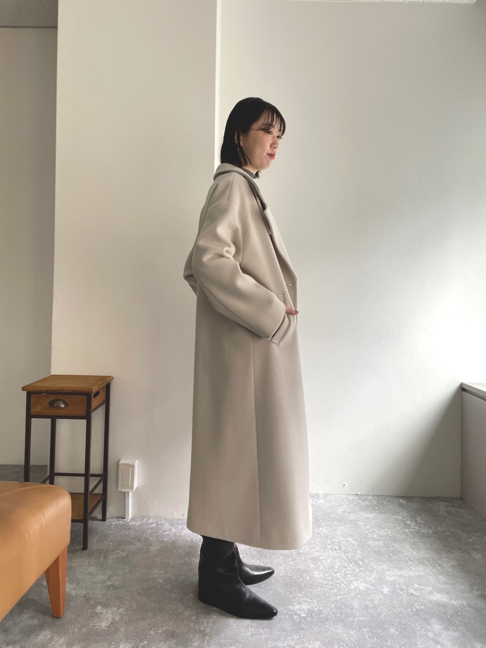 グレー系のニット/セーター、ベージュ系のチェスターコート、ブルー系のワンピースを着用したレディースの秋コーディネートの2枚目の写真