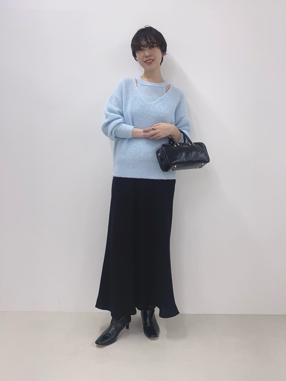 ブルー系のニット/セーター、ブラック系のスカート、ブラック系のボストンバッグを着用したレディースの冬コーディネートの2枚目の写真
