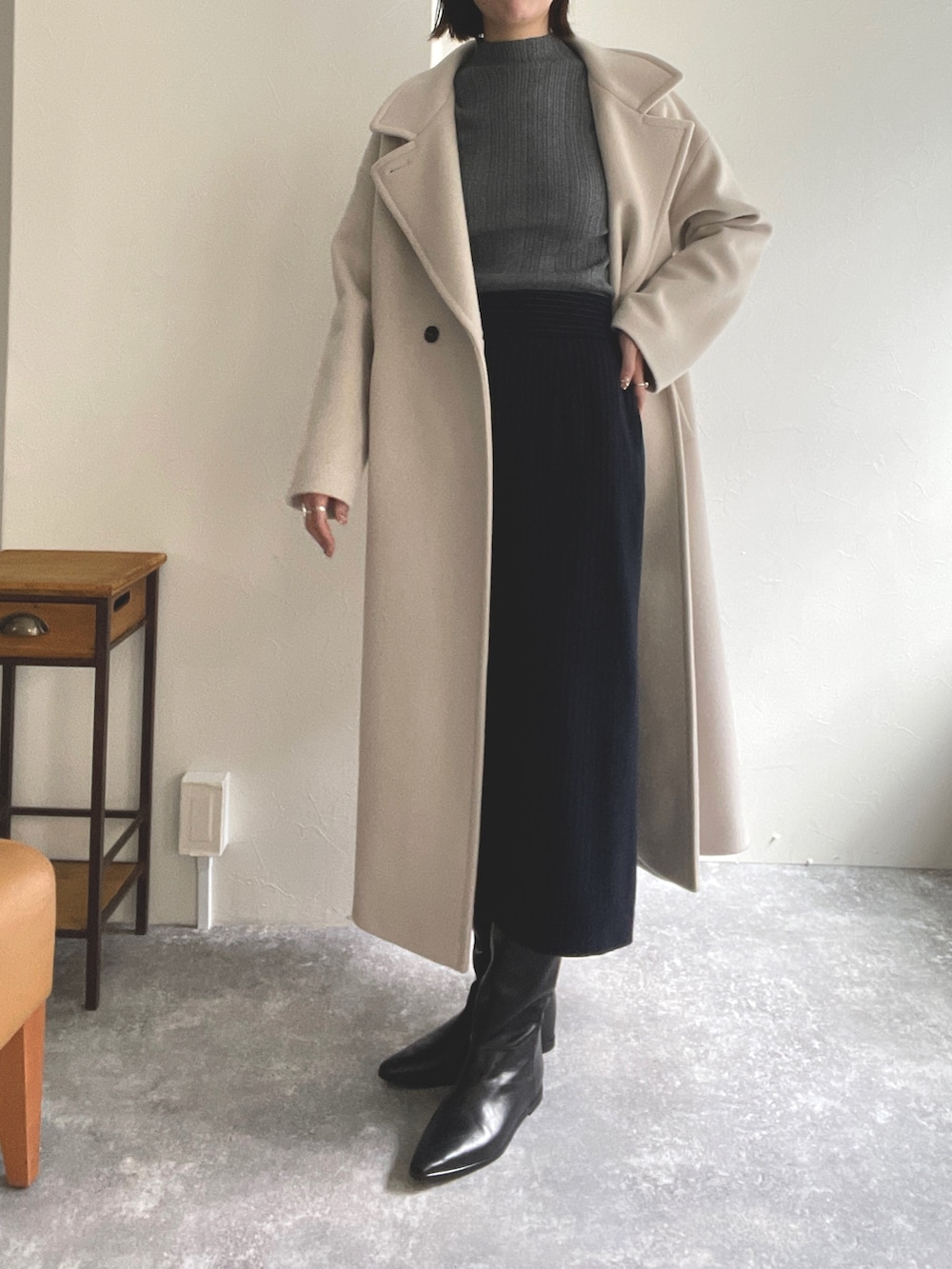 グレー系のニット/セーター、ベージュ系のチェスターコート、ブルー系のワンピースを着用したレディースの秋コーディネートの4枚目の写真