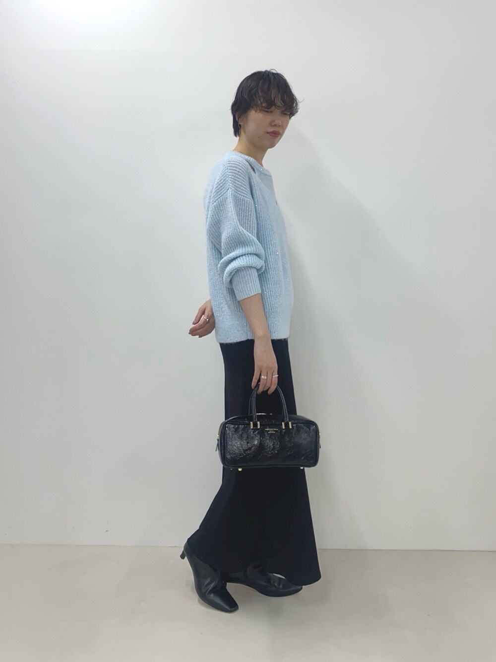 ブルー系のニット/セーター、ブラック系のスカート、ブラック系のボストンバッグを着用したレディースの冬コーディネートの4枚目の写真