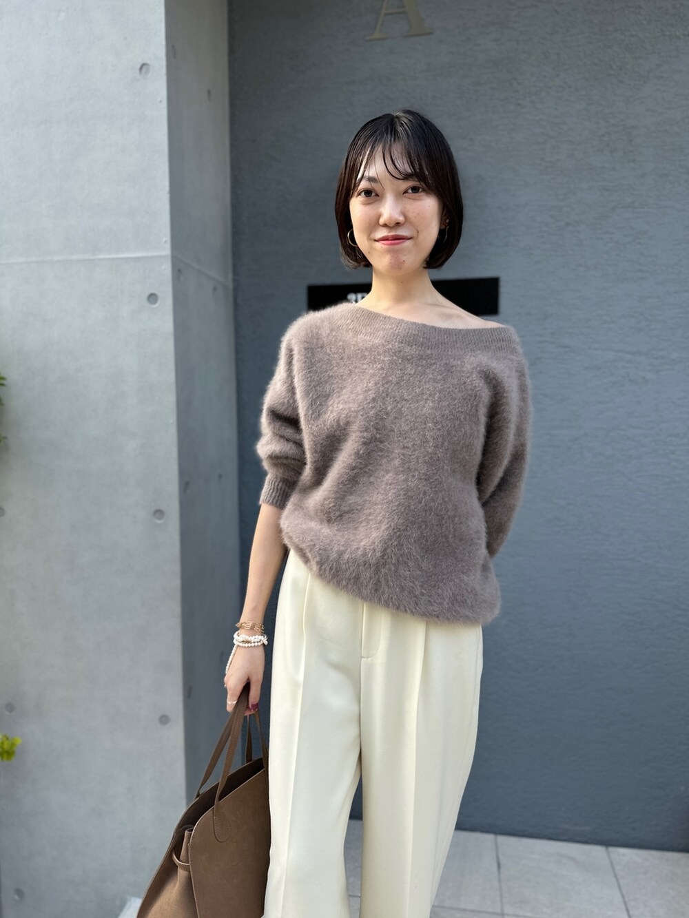 ブラウン系のニット/セーター、ブラウン系のボストンバッグ、ホワイト系のその他パンツを着用したレディースの秋コーディネートの5枚目の写真