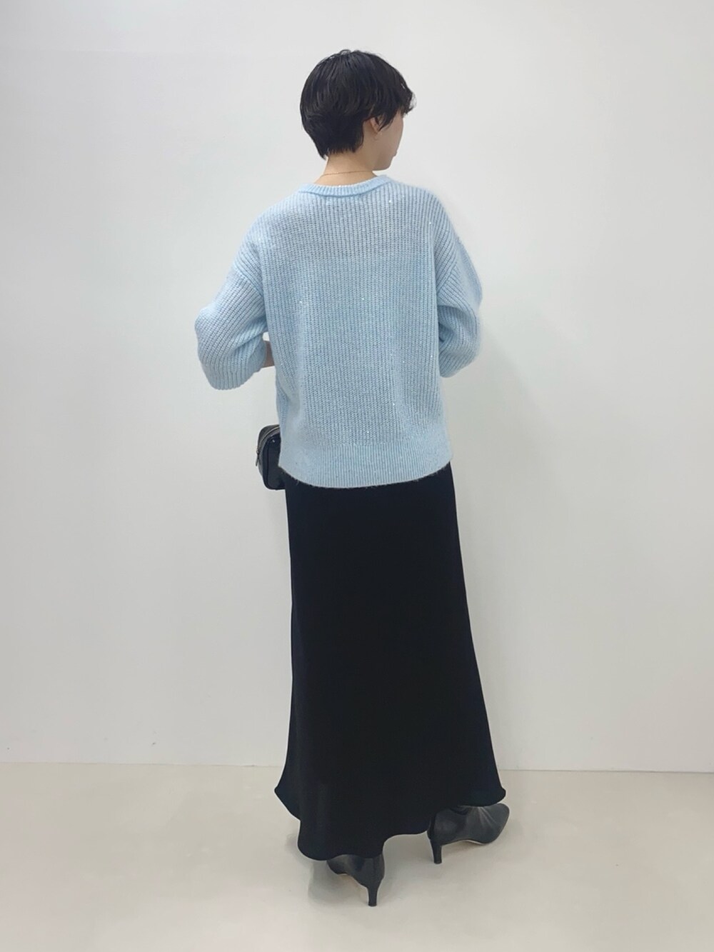 ブルー系のニット/セーター、ブラック系のスカート、ブラック系のボストンバッグを着用したレディースの冬コーディネートの3枚目の写真