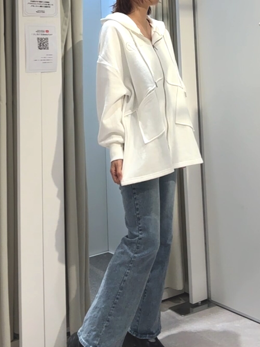 ホワイト系のパーカー、ブルー系のデニムパンツを着用したレディースの秋コーディネートの2枚目の写真