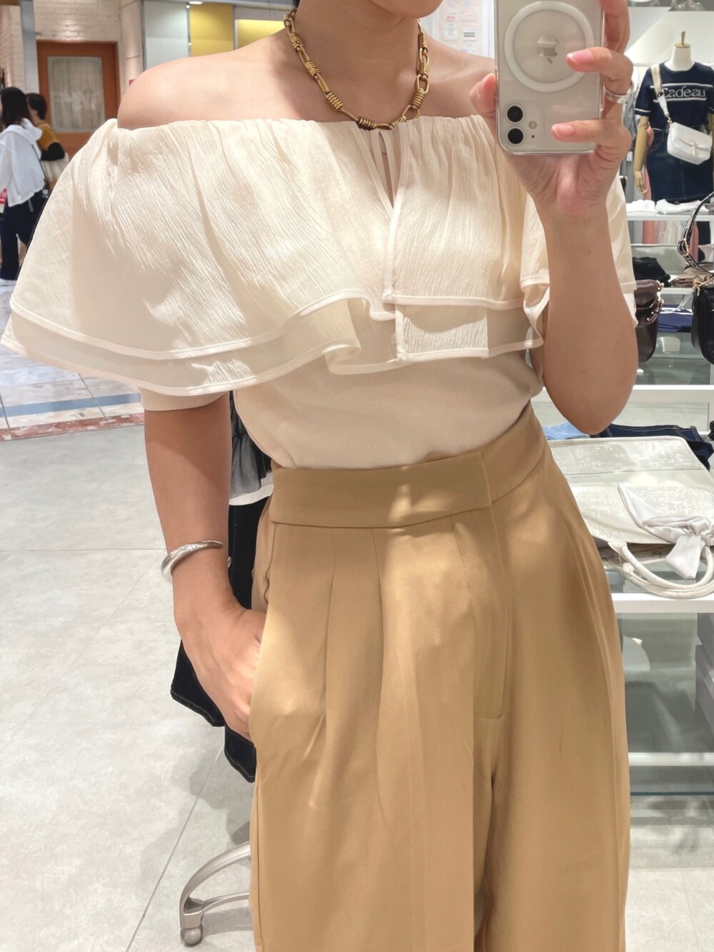 ベージュ系のスラックス、ホワイト系のTシャツ/カットソーを着用したレディースの夏コーディネートの2枚目の写真