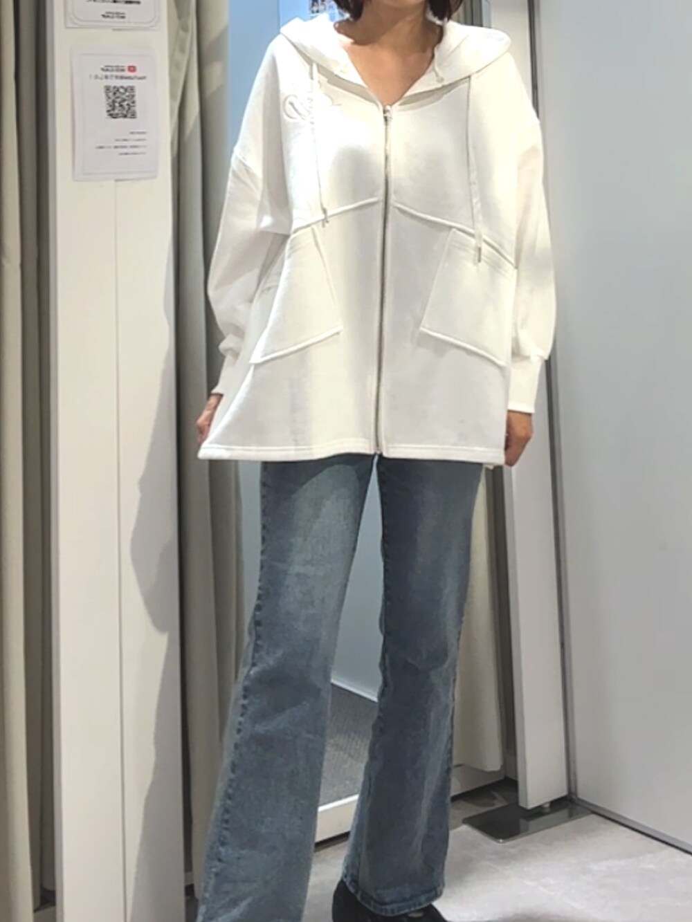 ホワイト系のパーカー、ブルー系のデニムパンツを着用したレディースの秋コーディネートの3枚目の写真