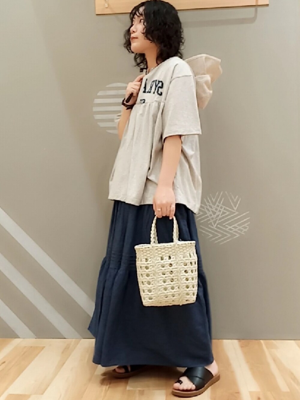 グレー系のTシャツ/カットソー、ブルー系のスカート、ホワイト系のハンドバッグを着用したレディースの夏コーディネートの2枚目の写真