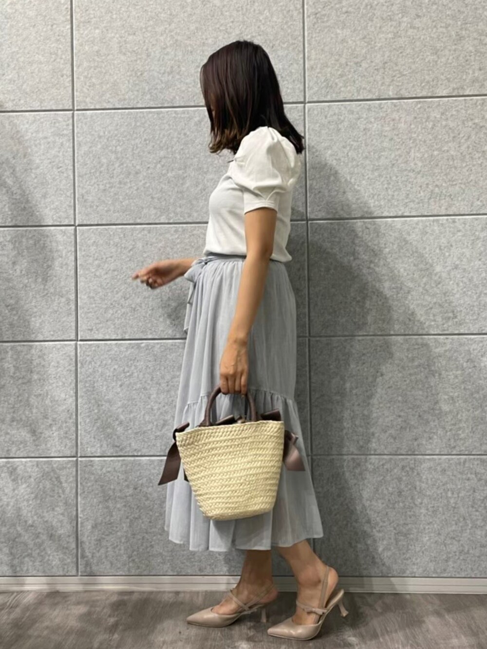 ベージュ系のハンドバッグ、ホワイト系のTシャツ/カットソー、ブルー系のスカートを着用したレディースの夏コーディネートの2枚目の写真