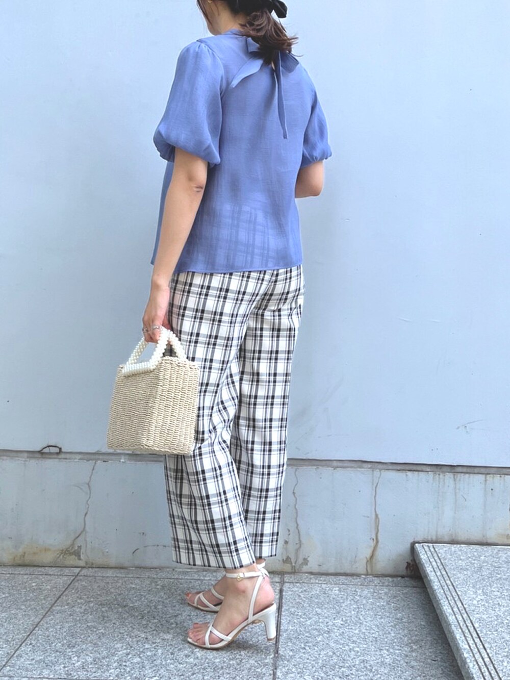 ベージュ系のハンドバッグ、ホワイト系のサンダルを着用したレディースの夏コーディネートの2枚目の写真