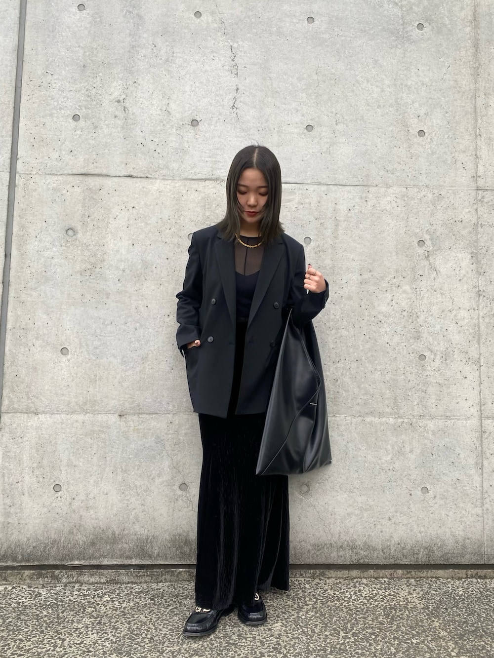 ブラック系のテーラードジャケット、ブラック系のトートバッグ、ブラック系のスカートを着用したレディースの春コーディネートの2枚目の写真