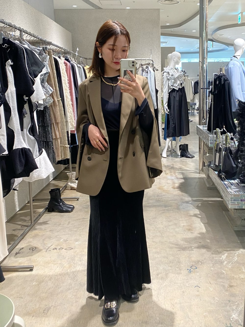 グリーン系のテーラードジャケット、ブラック系のスカート、ブラック系のキャミソールを着用したレディースの春コーディネートの2枚目の写真