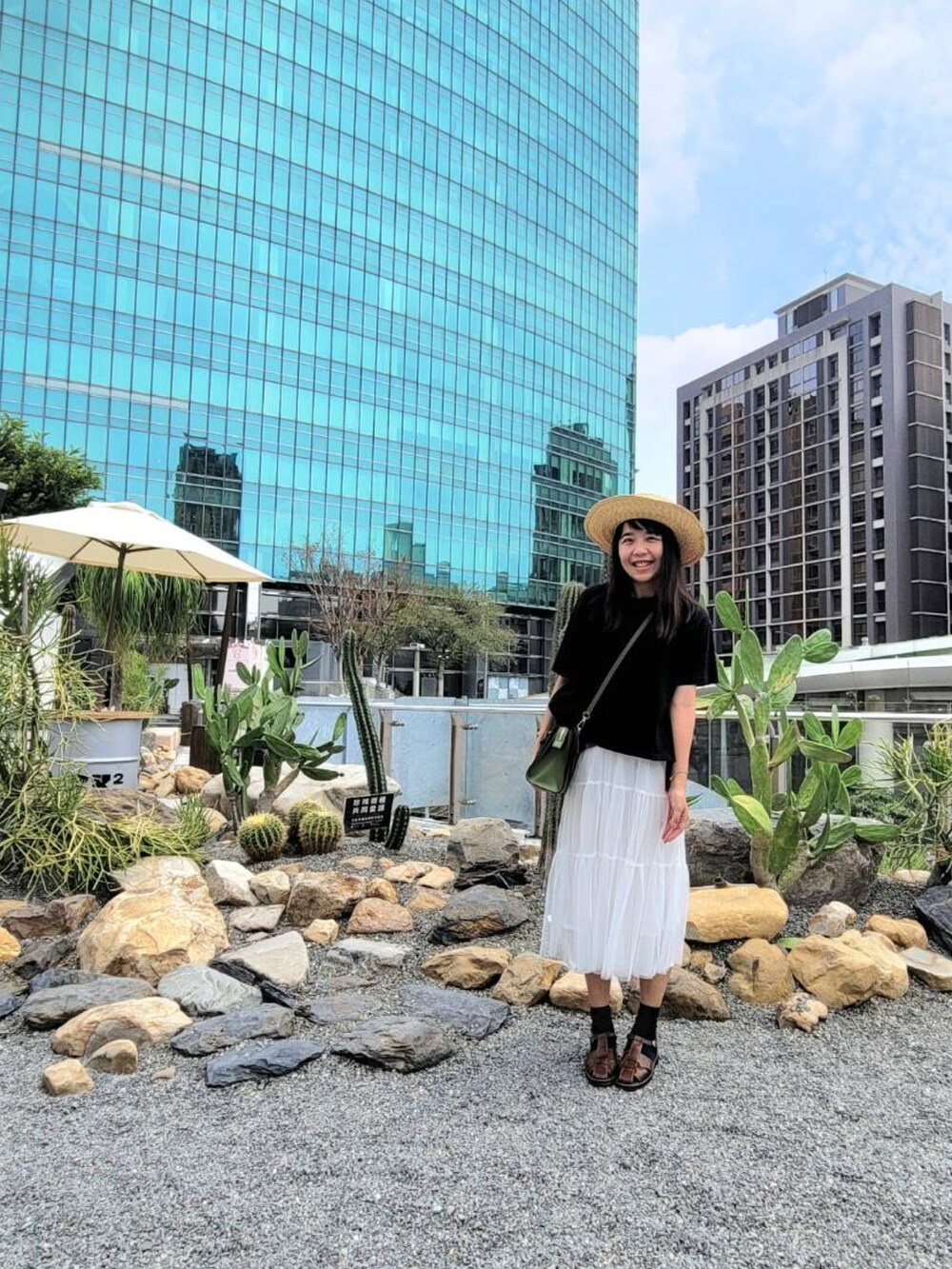 ブラウン系のサンダル、グリーン系のバッグ、ホワイト系のスカートを着用したレディースの夏コーディネートの2枚目の写真